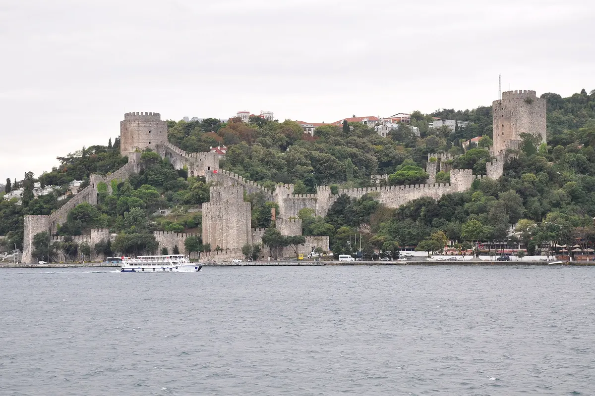 The Rumeli Fortress climbing a wooded hill above the Bosphorus, with stone towers and long crenellated walls.